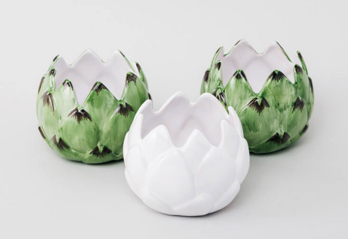 white artichoke candle holder on white table shown with green artichoke candle holders